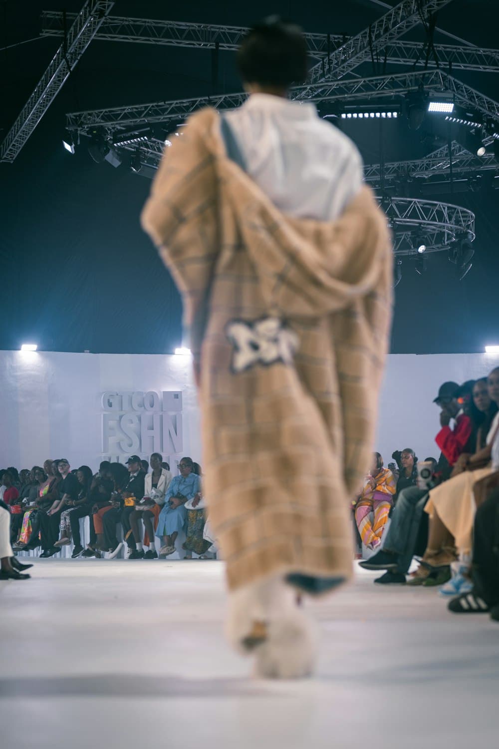 A model walking down a runway at a fashion show in Lagos