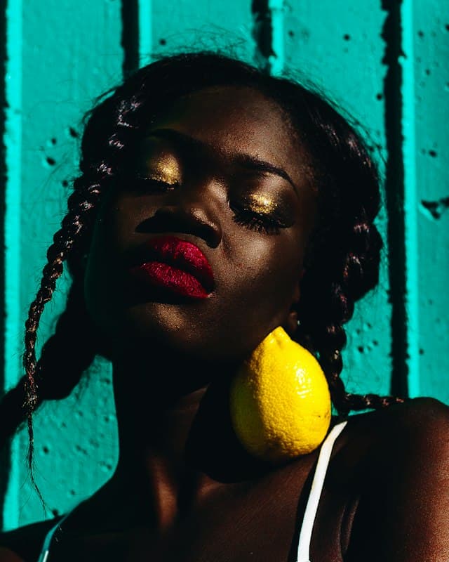 A beauty portrait with a slice of lemon against a teal backdrop